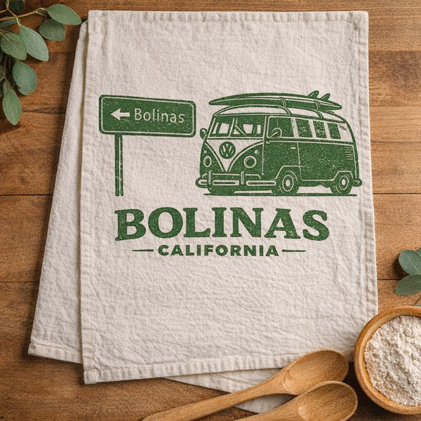 Kitchen towel with green graphic of a VW surf van and 'Bolinas California' text on a wooden surface.