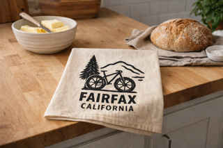 Kitchen towel with 'Fairfax California' design on a wooden countertop.